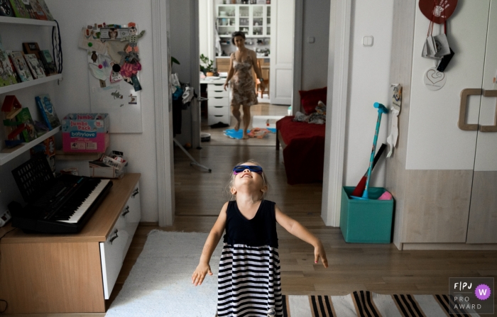 Gard, Frankreich Familienfotografie, die Mutter und Tochter dokumentiert, die zu Hause mit einer Sonnenbrille für das kleine Mädchen chillen