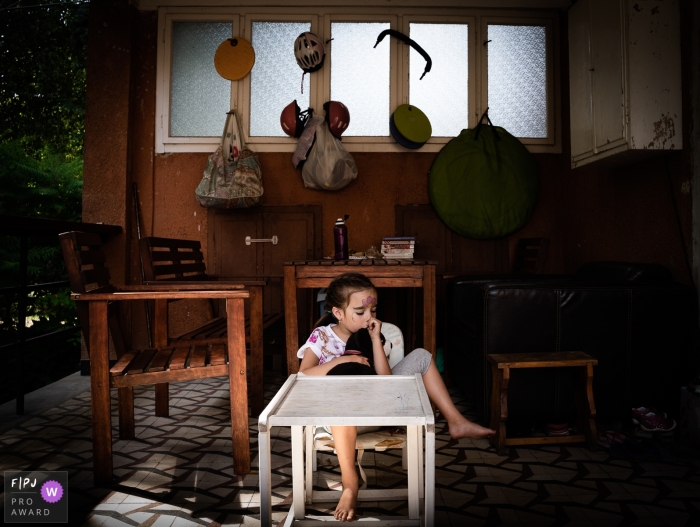 Nimes, Gard dokumentarische Familienfotografie, die ein müdes Mädchen aufzeichnet, das zu Hause auf einem Stuhl an einem Tisch sitzt