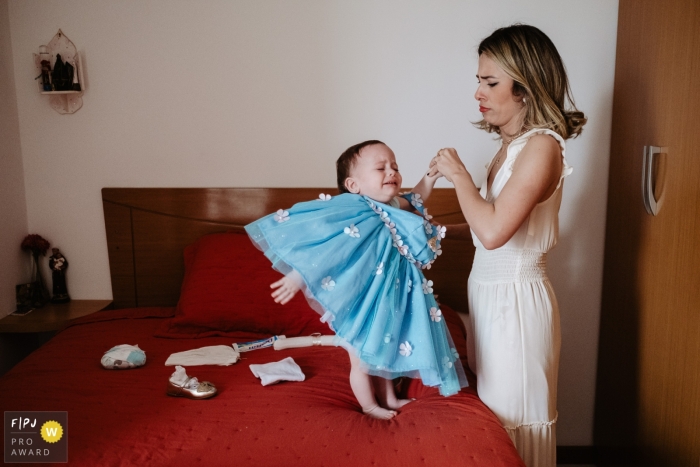 Ein dokumentarischer Familienfotograf aus Santa Catarina hat diese Mutter aufgenommen, die ihrer Tochter ein Geburtstagskleid anzieht