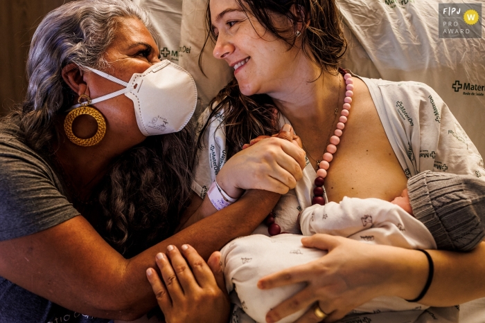 Image de naissance de style documentaire primée de Mater Dei à Minas Gerais Capturer le moment où la gratitude s'exprime dans le regard entre la femme et sa doula après l'accouchement