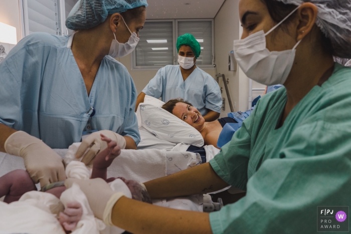 Prämiertes Geburtsfoto im Dokumentarstil von Maternidade Pro Matre in Sao Paulo, auf dem Mama und Papa ihr neugeborenes Baby beobachten