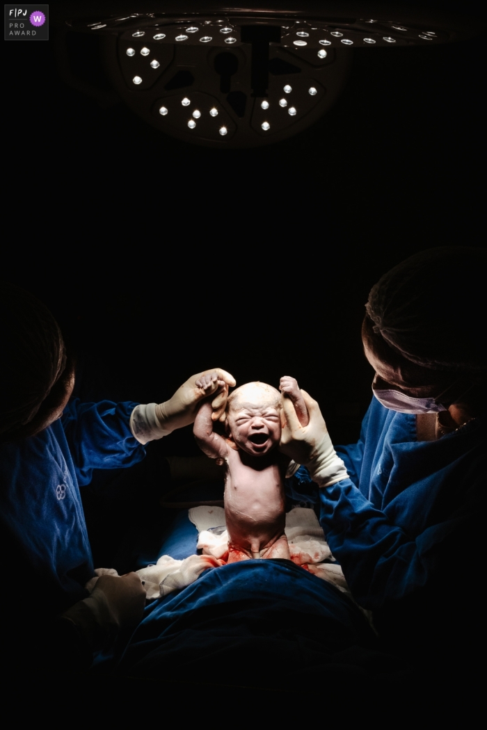 Photo de naissance récompensée de Santa Catarina à Maternidade Santa Helena montrant deux obstétriciens soulevant le bébé et la mettant au monde, la tenant dans leurs bras