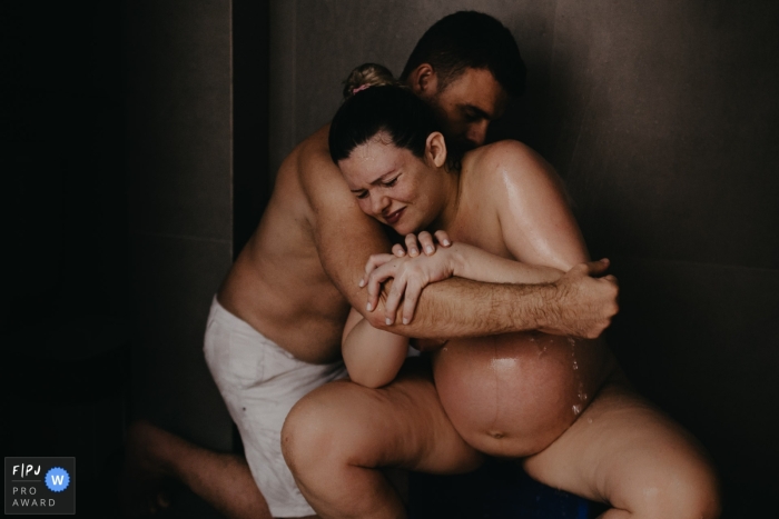 Awarded documentary style birth photo from Maternidade Santa Helena in Santa Catarina, Brazil as mom and dad work through labor together Awarded documentary style birth photo from Maternidade Santa Helena in Santa Catarina, Brazil as mom and dad work through labor together