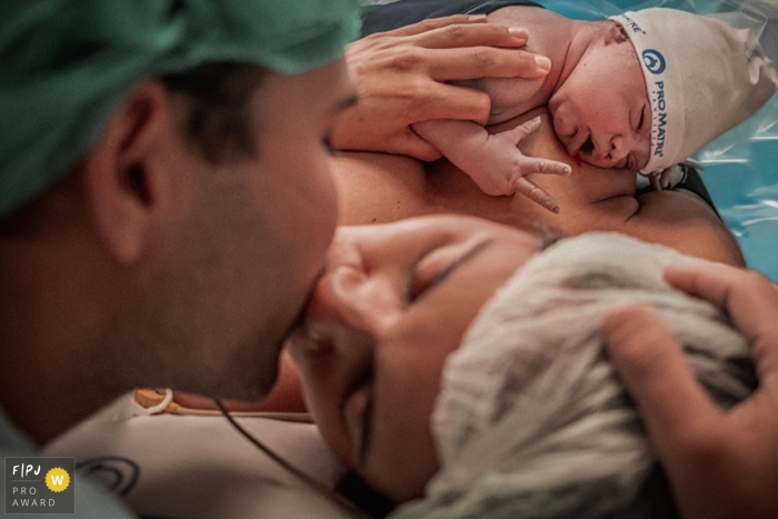 Awarded documentary style birth photo from Pro Matre in SP, Brazil showing the Parents seal the birth of their daughter with a kiss Awarded documentary style birth photo from Pro Matre in SP, Brazil showing the Parents seal the birth of their daughter with a kiss