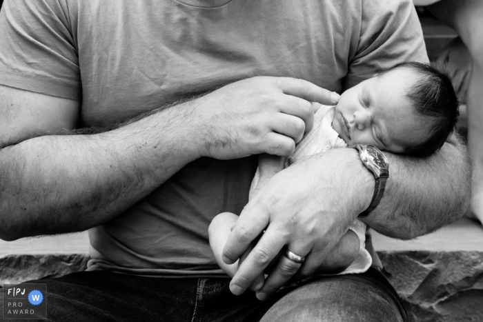 Preisgekröntes dokumentarisches Familienfoto aus Toronto, das Papa zeigt, wie er seine schlafende neugeborene Tochter hält, während sie unbeholfen in seinen Armen schläft