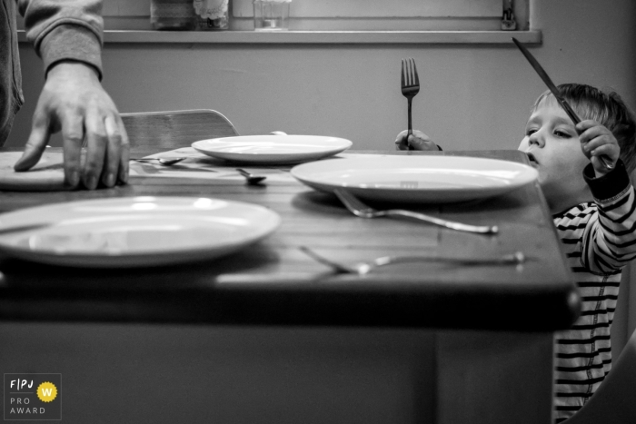 Photographie de famille documentaire à Düsseldorf en BW d'un petit garçon Mettre la table pour un repas