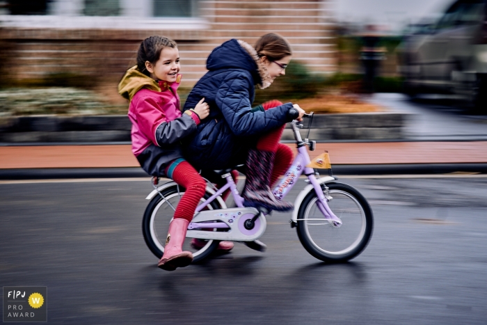 Bekroonde documentaire familieshow sluiterfoto uit Noord-Rijnland-Westfalen van zusters die op de fiets los gaan op straat