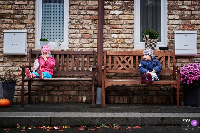 A Bonn, Germany documentary family photographer captured this image of two kids sitting on wooden benches outside