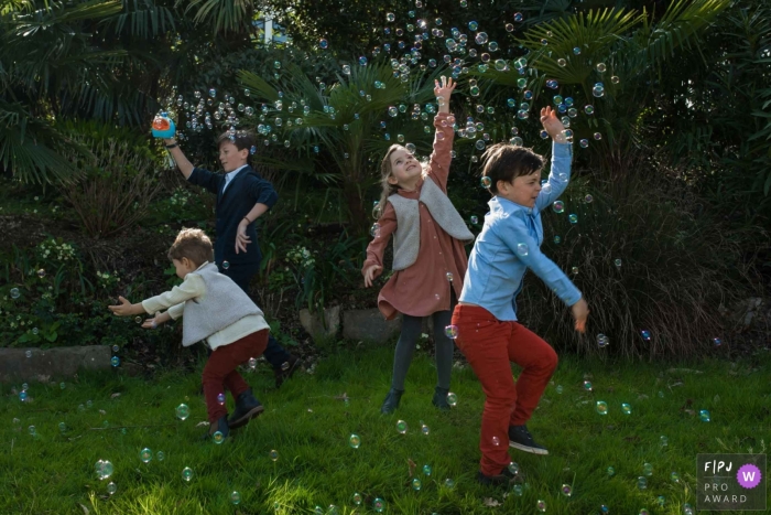 Séance photo documentaire famille landaise avec des enfants Jouer avec des bulles dans le jardin