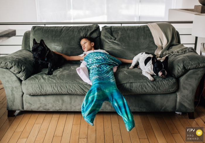 Photo de famille documentaire primée de Mexico d'un jeune enfant sur le canapé partageant du temps avec deux chiens