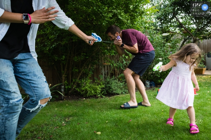 A United Kingdom documentary family photographer captured this Family water pistol fight in the garden A United Kingdom documentary family photographer captured this Family water pistol fight in the garden