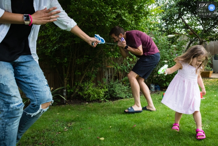 Ein dokumentarischer Familienfotograf aus dem Vereinigten Königreich hat diesen Wasserpistolenkampf der Familie im Garten festgehalten