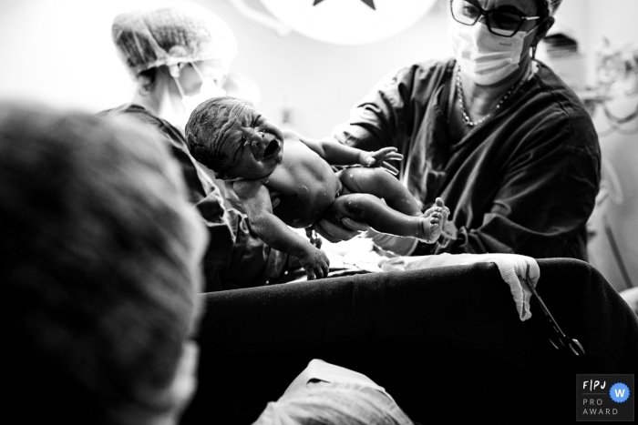 Santa Catarina birth documentary photography in BW showing the baby boy arriving to the delivery room doctors