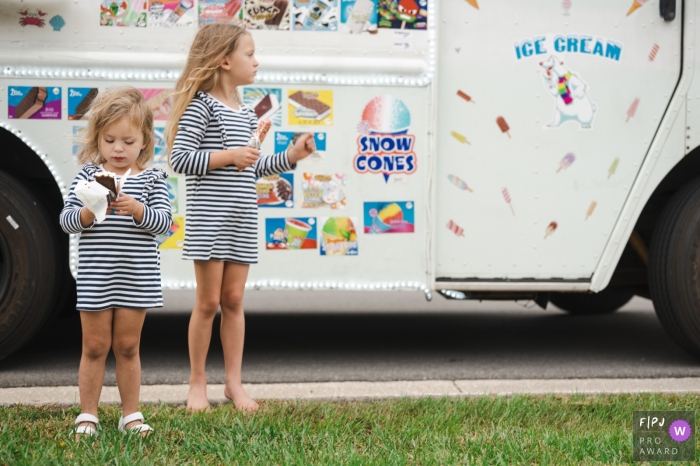 Song of the Sarasota ice cream truck while they were playing in their yard scored these sisters a sweet after dinner dessert during a family documentary photography session in Florida Song of the Sarasota ice cream truck while they were playing in their yard scored these sisters a sweet after dinner dessert during a family documentary photography session in Florida