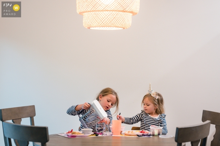 Sarasota documentary style photography from a family session created as Sisters are having their dinner time at the dinner table