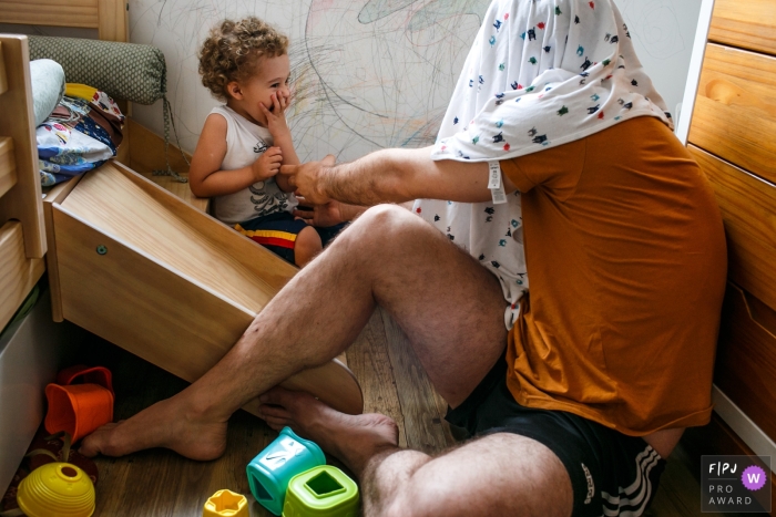 Photographie de style documentaire de Belo Horizonte lors d'une séance familiale dans le Minas Gerais capturant la joie de l'enfant avec le jeu inventé par le père