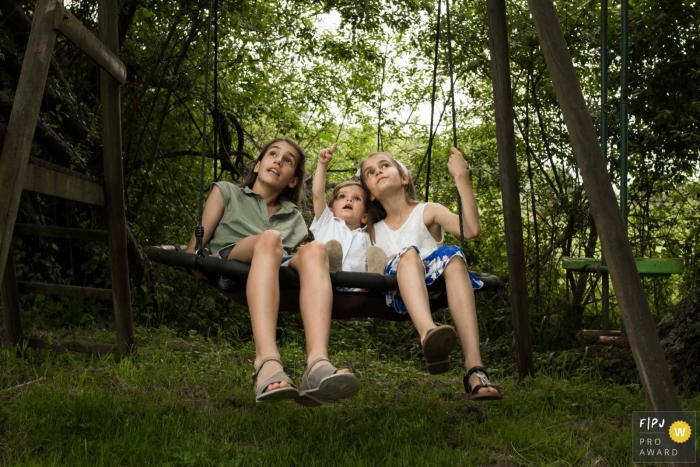 Séance photo de famille documentaire landaise en Nouvelle Aquitaine, France montrant des frères et sœurs sur une balançoire écoutant les plus jeunes