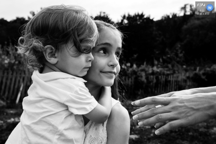 Photographie landaise style documentaire d'une séance famille montrant un enfant tenant son petit frère dans ses bras