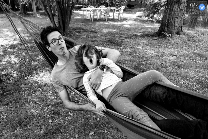 Father and son in playing together in a hammock during a BW family documentary photography session in Paris, France Father and son in playing together in a hammock during a BW family documentary photography session in Paris, France