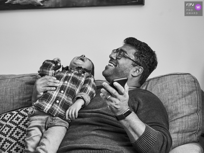 Documentary family photojournalism from Lancashire, England capturing a toddler Laughing along with Dad