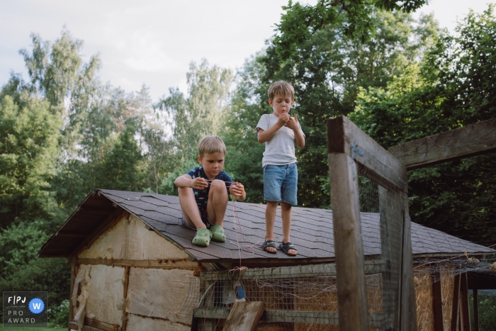 Documentary family photojournalism from Tallinn, Estonia with playful children on the roof of the chicken coop Documentary family photojournalism from Tallinn, Estonia with playful children on the roof of the chicken coop
