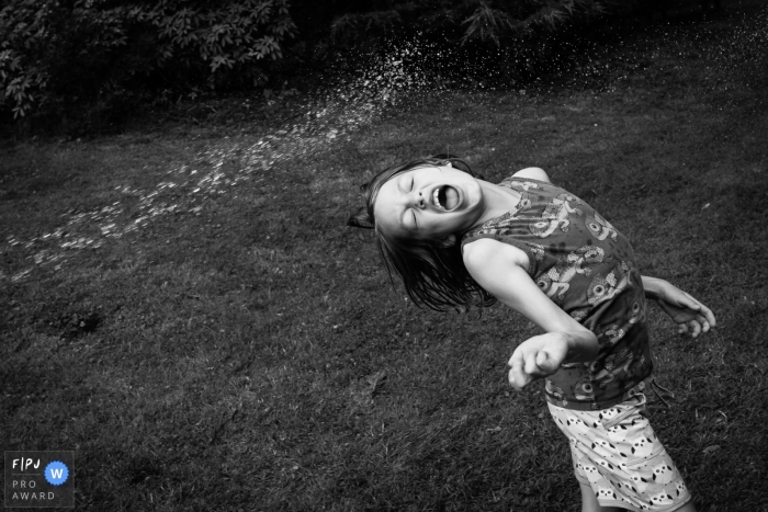 Documentaire familiefotosessie in een huis in Cambridgeshire, VK, waarin een jongen met water uit de tuinslang te zien is