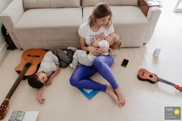 Photojournalisme familial documentaire de Florianopolis, Santa Catarina enregistrant une mère allaitant un enfant, dans le désordre de son salon, l'autre s'endormant allongée sur le sol à côté d'elle