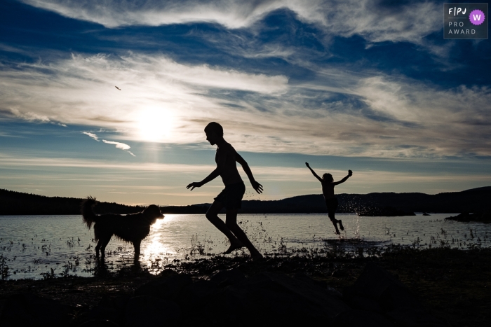 Kinder in Norwegen spielen während des Sonnenuntergangs am Rand des Wassers