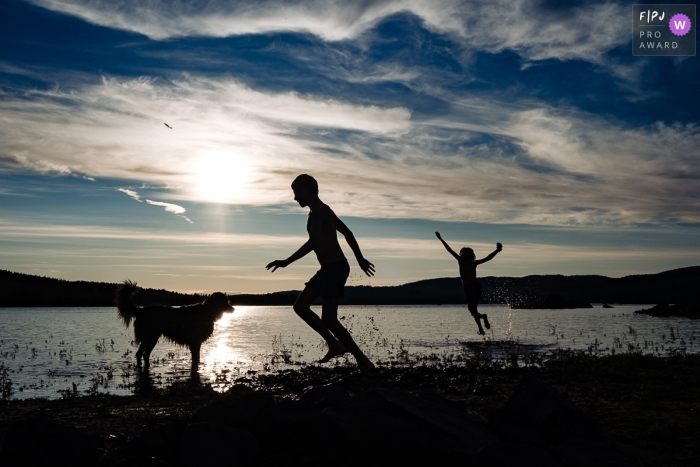 Children in Norway play at the edge of the water during sunset Children in Norway play at the edge of the water during sunset