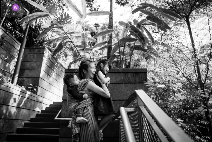 mum is carrying her girl to a higher vantage point to see the garden across the railings A Singapore mum is carrying her girl to a higher vantage point to see the garden across the railings