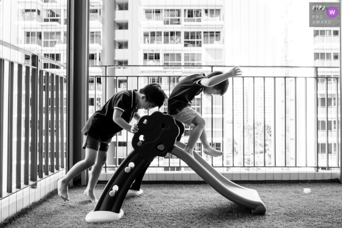 Big brother head-butted his little brother's butt on their balcony play slide In Singapore Asia, a Big brother head-butted his little brother's butt on their balcony play slide