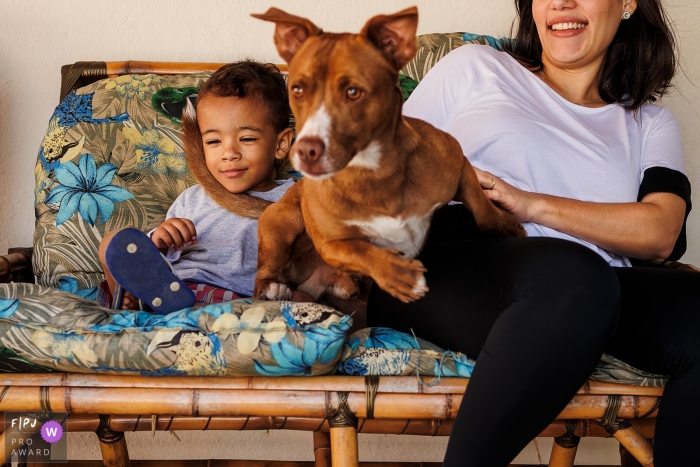 Een Minas Gerais-hond die in een plotselinge beweging naar beneden gaat om te rennen, maakt een delicaat gebaar van genegenheid met de staart op het gezicht van het kind thuis in Belo Horizonte