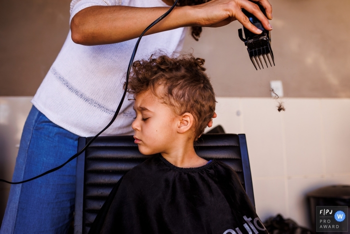 De concentratie van het kind Belo Horizonte toen zijn moeder thuis in Minas Gerais voor het eerst de krullen van zijn haar knipte