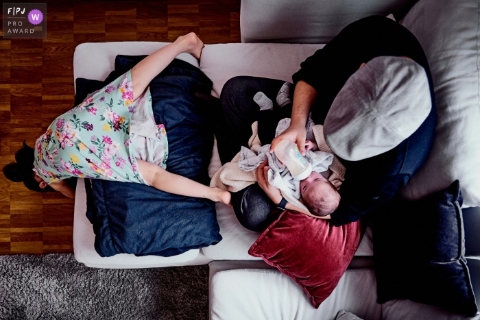 girl is playing at the couch while her dad is feeding a baby inside their home A Bonn girl is playing at the couch while her dad is feeding a baby inside their home in North Rhine-Westphalia