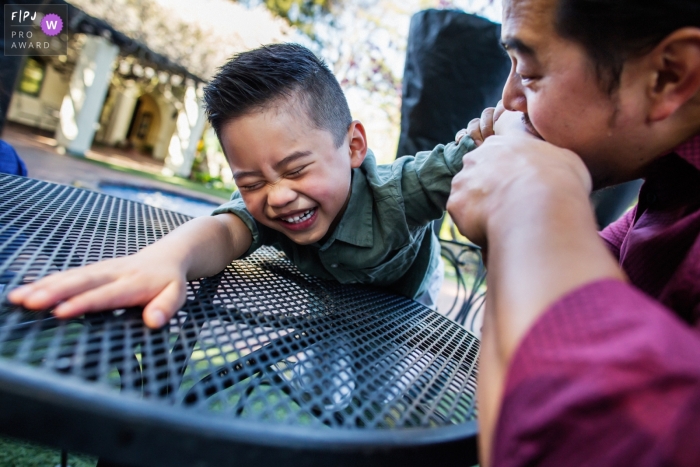 big boy is giggling hard with Dad munching on his elbow A San Francisco big boy is giggling hard with Dad munching on his elbow