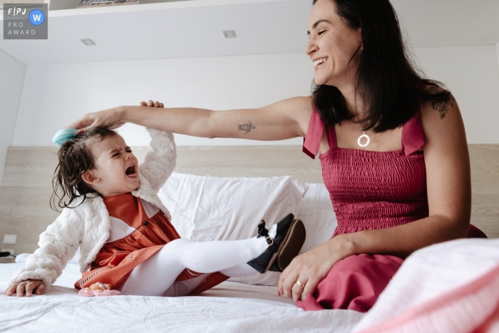 A Florianopolis mother trying to comb her daughter's hair on her birthday, with crying, sleepy daughter in bed at home in St. Catarina A Florianopolis mother trying to comb her daughter's hair on her birthday, with crying, sleepy daughter in bed at home in St. Catarina