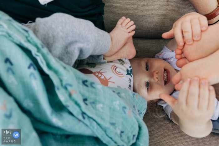 A Madison, Wisconsin preschool girl examines toes while newborn sibling's toes right above her A Madison, Wisconsin preschool girl examines toes while newborn sibling's toes right above her