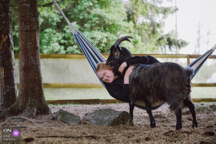 Een kind speelt met haar geit terwijl ze in een hangmat schommelt in de provincie Tallinn Harju