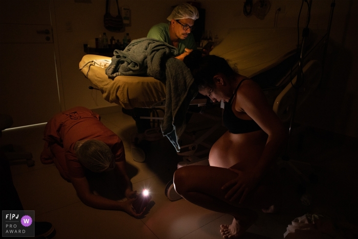 At Santa Clara hospital, a nurse watches a mother in labor while the father checks his cell phone