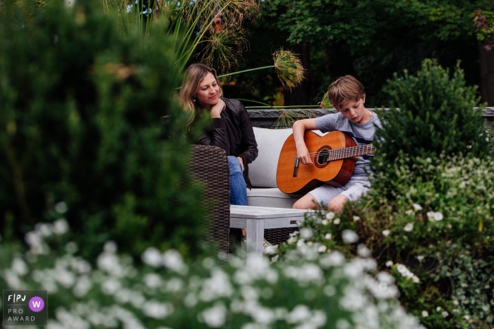 Une mère regarde avec amour son fils jouer de la guitare dans un parc pittoresque du New Hampshire, aux États-Unis