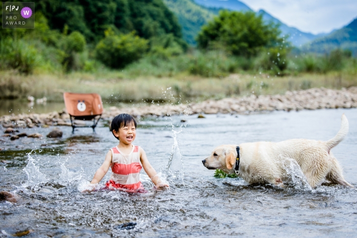 In Hangzhou City, Zhejiang Province, the boy and his faithful pooch had fun playing in the creek bed with its stone-lined banks The boy and his loyal canine companion enjoyed playing in the creek bed, complete with its stone-lined banks, in Hangzhou City, Zhejiang