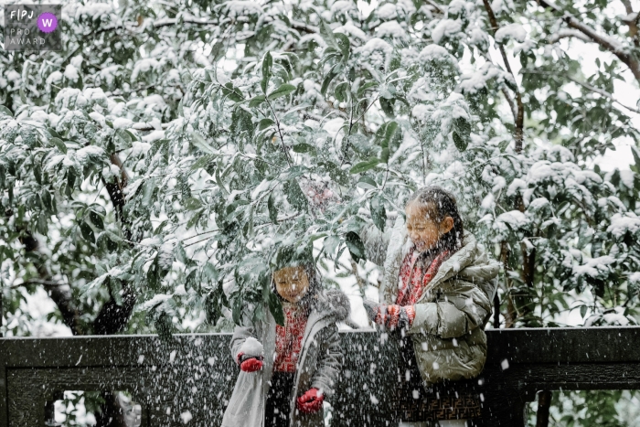 Zwei Schwestern erfreuen sich am Schneefall in der Stadt Hangzhou, Zhejiang, während sie spielerisch die Schönheit des Winters genießen