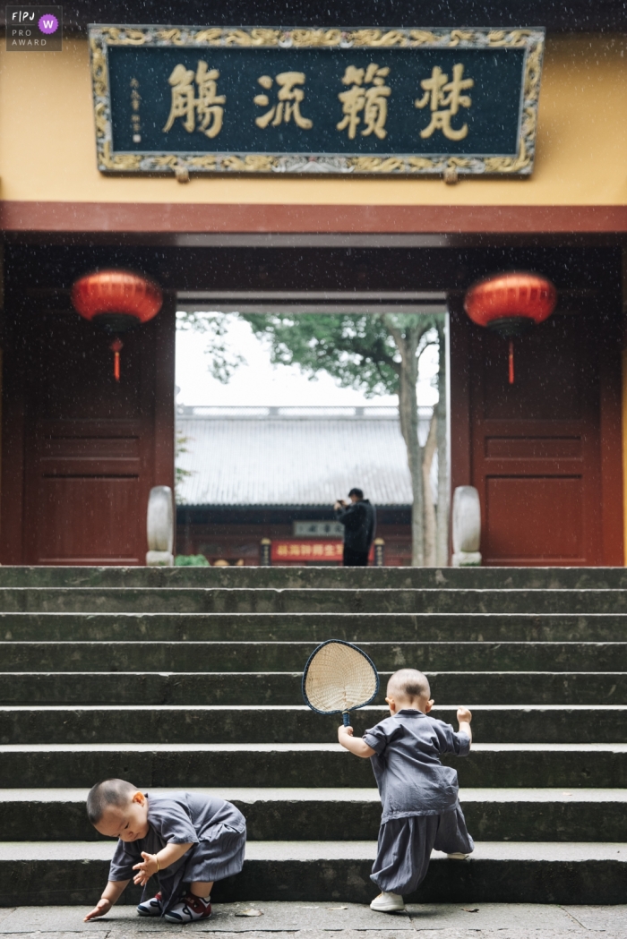 Die beiden Brüder können glücklich spielen und die Treppen des Tempels in der Stadt Hangzhou, Zhejiang, hinaufsteigen, gekleidet in traditionelle Zen-Kleidung