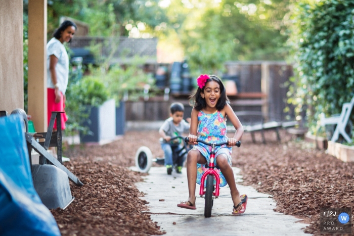 De broers en zussen hadden een leuke tijd met fietsen door het huis, terwijl mama een oogje in het zeil hield terwijl ze over het met mulch omzoomde trottoir in San Francisco, Californië, fietsten